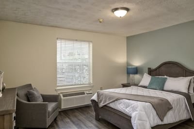 Cozy resident room with bed and seating area.