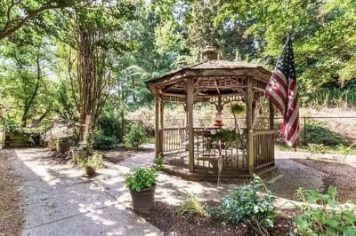 Gazebo in a landscaped outdoor space with an American flag.