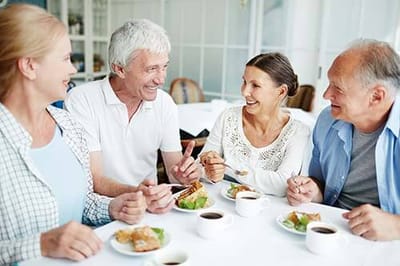 Four residents enjoying a meal and conversation.