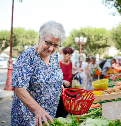 Senior woman shopping at a vibrant outdoor market.