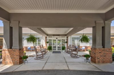 Covered entrance with rocking chairs and planters.