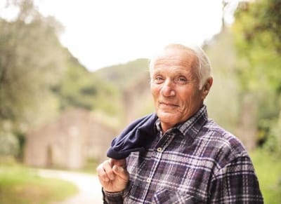 Smiling senior man outdoors with nature background.