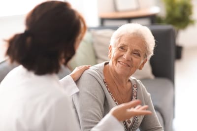 Caregiver conversing with a smiling senior resident.