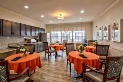 Dining area with orange tablecloths and kitchen