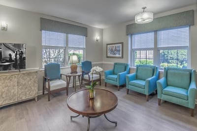 Bright common area with teal chairs and a table.