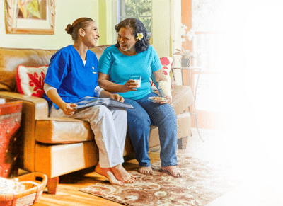 A nurse and resident laughing together in a cozy living room