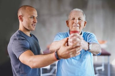 Senior man exercising with therapist’s assistance