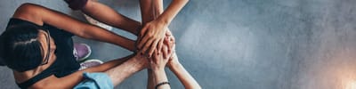 Several hands joining together in a supportive gesture.