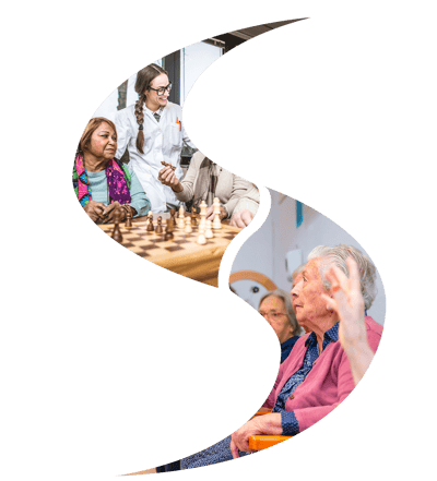 Engaged residents and staff playing chess indoors.
