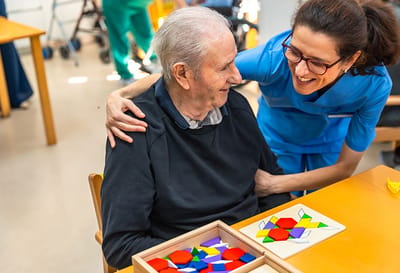 Caregiver engaging with a senior resident during an activity.
