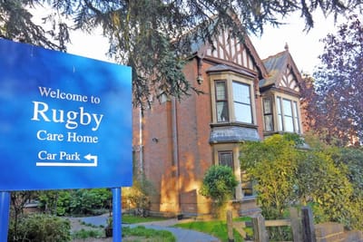 Exterior view of Rugby Care Home with welcome sign.
