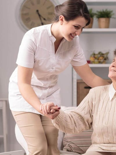 Caregiver assisting an elderly woman in a cozy setting.