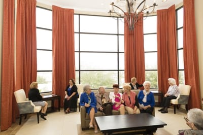 Residents socializing in a common area with large windows.