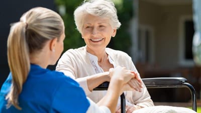 A caregiver and a resident chatting outdoors.