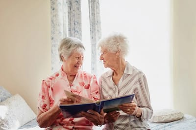 Two elderly women sharing a photo album