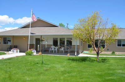 Exterior view of a senior care facility with lawn and porch.