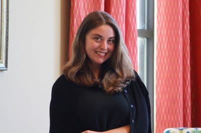 A staff member smiling in a cozy interior setting.