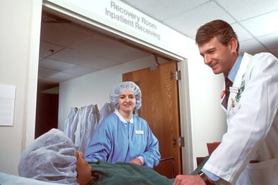 Medical staff interacting with a patient in a recovery room.