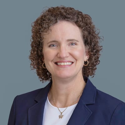 Portrait of a smiling woman in professional attire.
