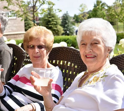 Two elderly women enjoying drinks outdoors.