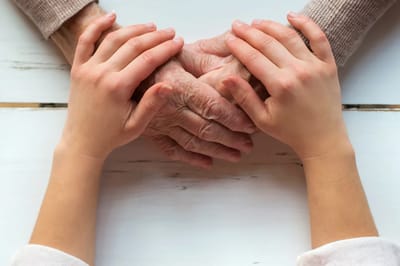Hands of a caregiver and a senior holding each other