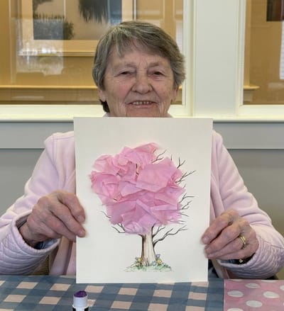 Resident holding an art project in the activity room