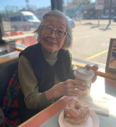 Elderly woman enjoying a donut and coffee