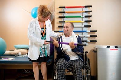 Staff assisting a resident in therapy exercise