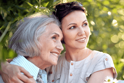 An elderly resident with a caregiver in a garden