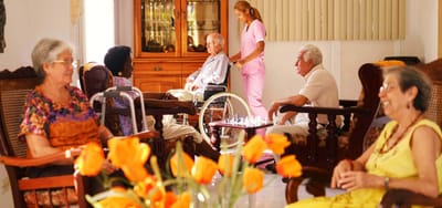 Residents socializing in a common area with a caregiver