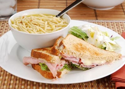 A plate of sandwich and soup with salad