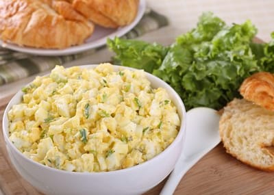 Bowl of egg salad with croissants and lettuce