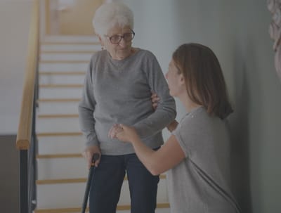 A caregiver assisting a senior woman on stairs