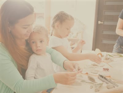 Children crafting with an adult in a light setting