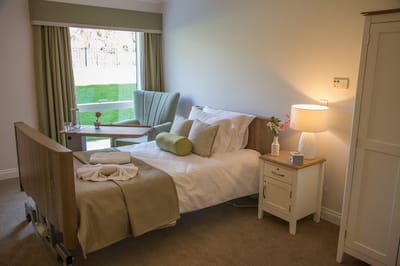 A well-furnished private resident room with a bed and seating area.