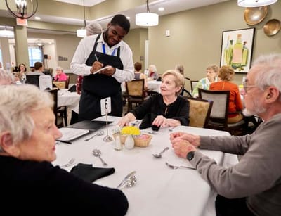 Table setting in a dining room with staff serving residents