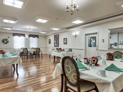 Dining room set up for a meal with tables and flowers
