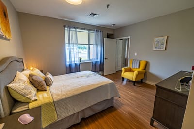 Cozy private resident room with a bed and chair