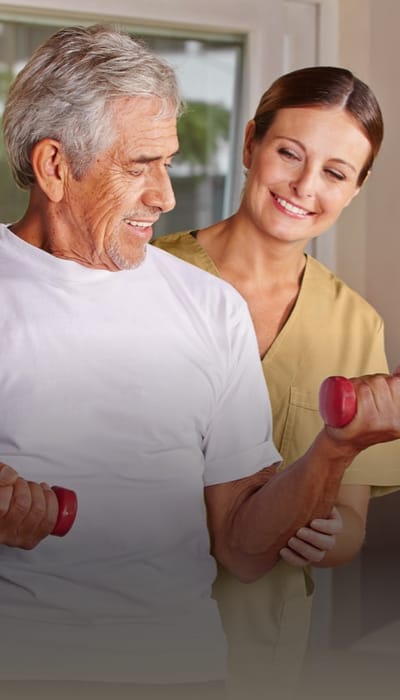 Staff assisting a resident with weights in an activity room