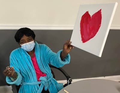 Resident painting a heart on canvas during an activity