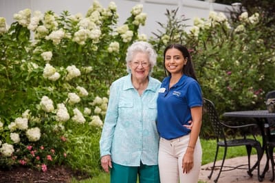 Resident and staff member smiling in a garden