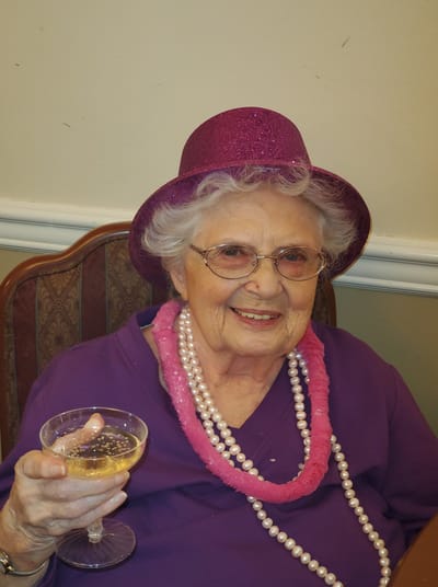 Resident enjoying a celebration with a drink and festive attire