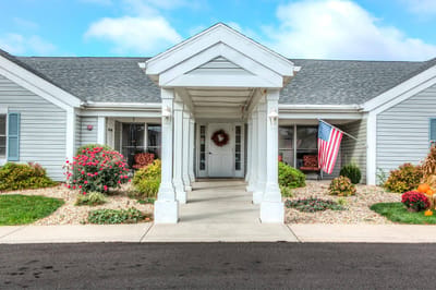 Front entrance of a senior living facility with flowers and an American flag