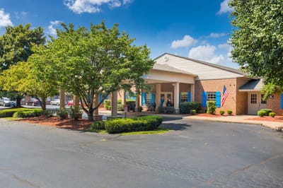 Exterior view of Charter Senior Living with trees and American flag