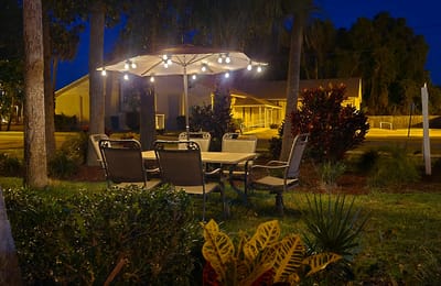 Outdoor seating area with a lit umbrella and chairs.