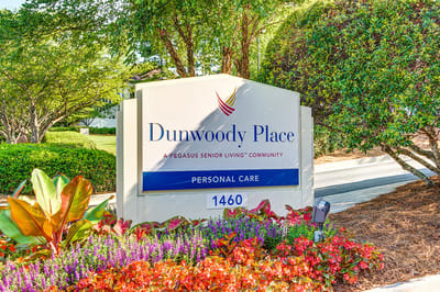 Facility sign for Dunwoody Place with colorful landscaping