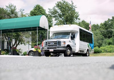 Facility shuttle bus parked in front of a canopy entrance