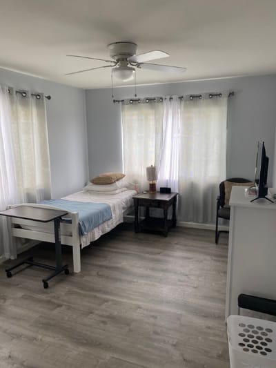 A private resident room with a bed and chair