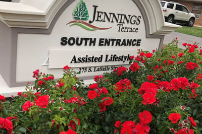 Sign at the South Entrance of Jennings Terrace with flowers