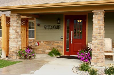 Exterior entrance with welcome sign and flowers